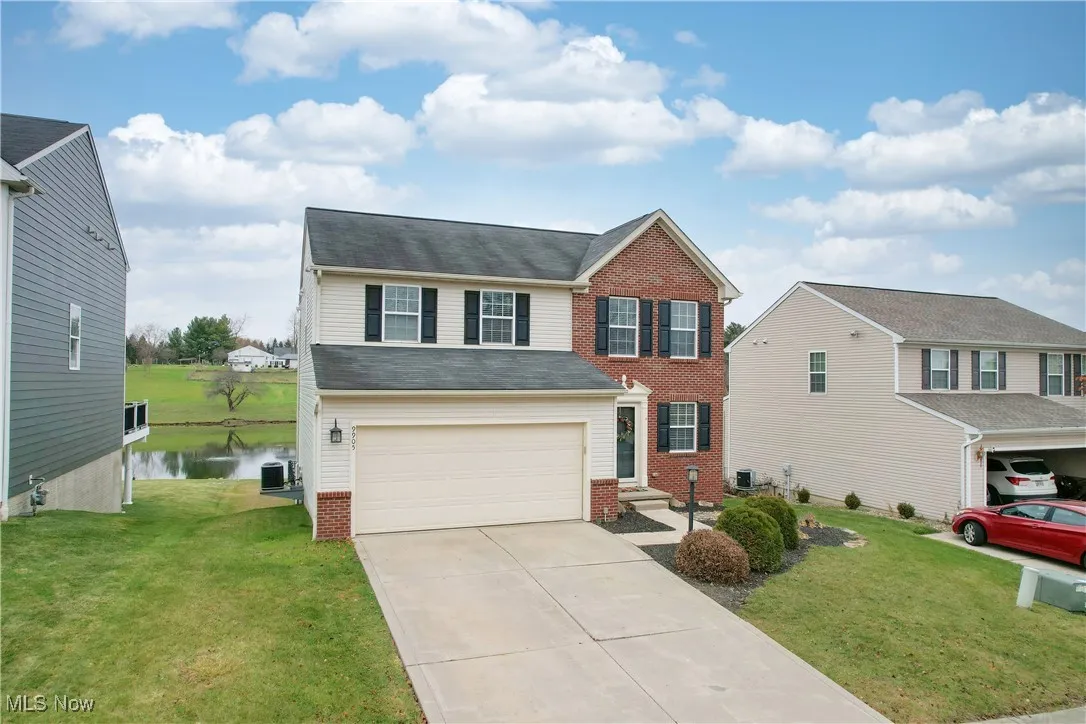 View of front of house with a front yard, concrete driveway, a garage, and brick siding