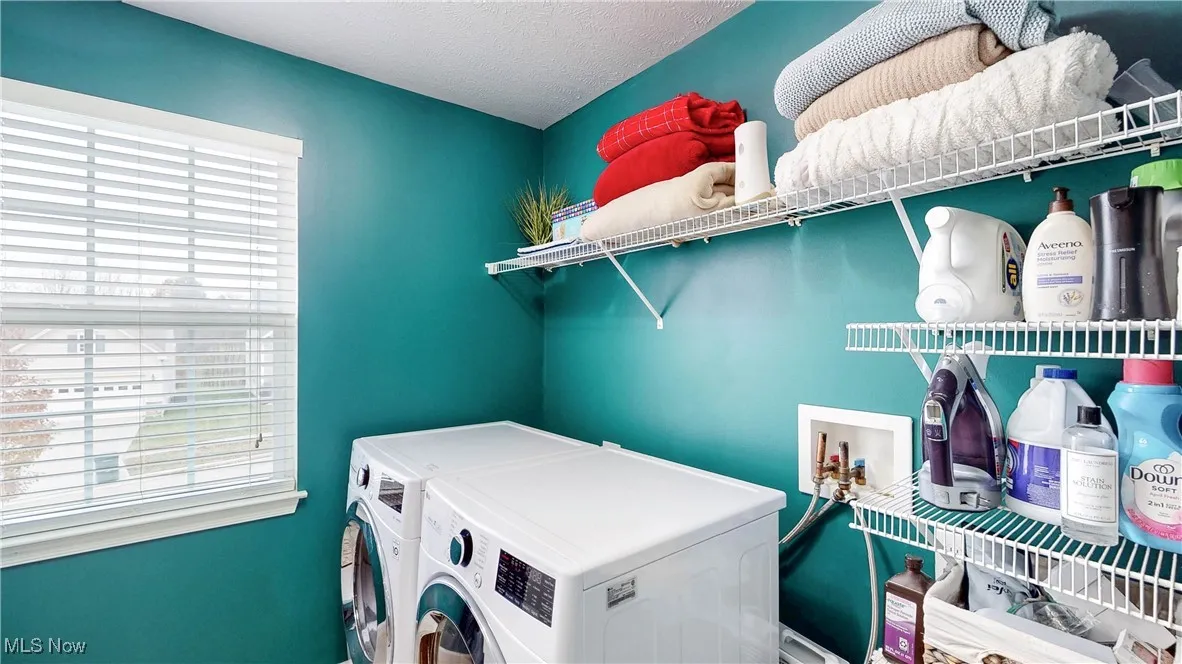 Laundry room with washing machine and dryer and a textured ceiling