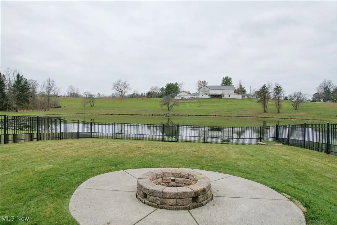 Fenced backyard featuring a water view, an outdoor fire pit, and a patio