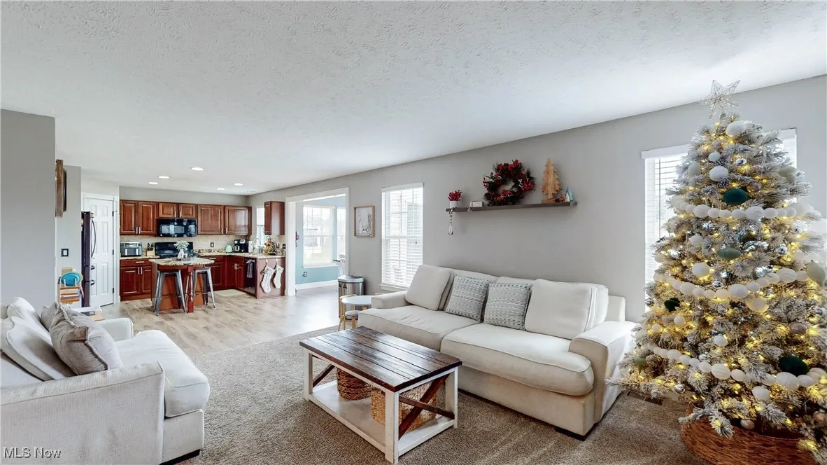 Living room featuring light wood-style floors, a textured ceiling, and recessed lighting