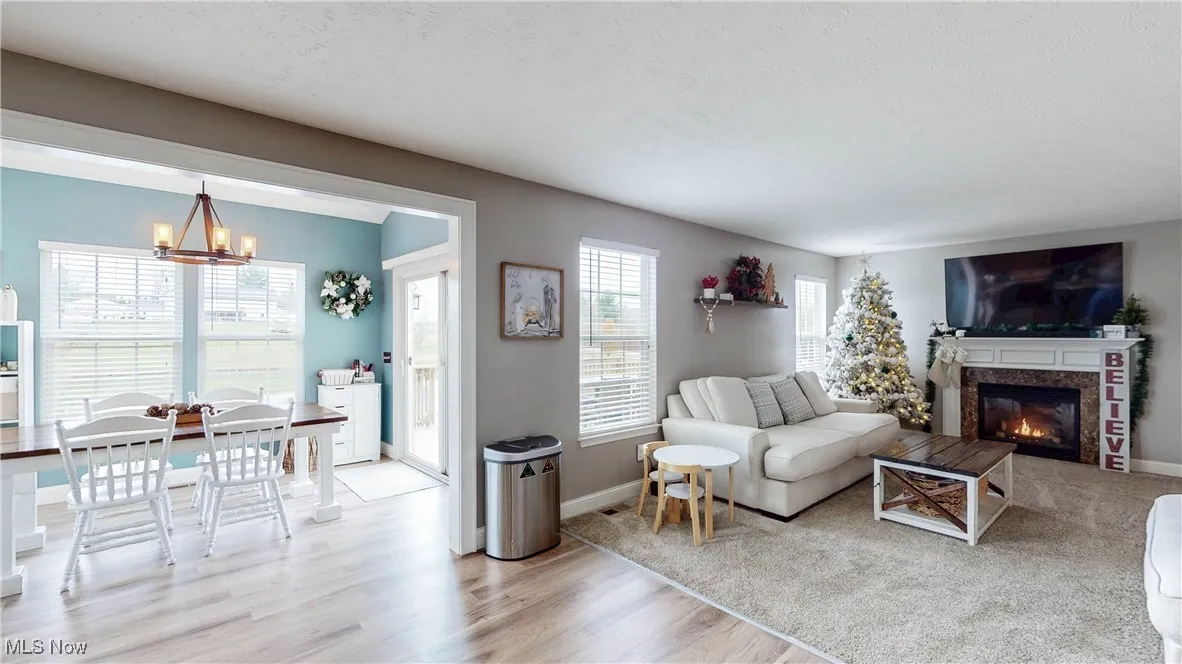 Living area with light wood finished floors, a chandelier, a premium fireplace, and a textured ceiling