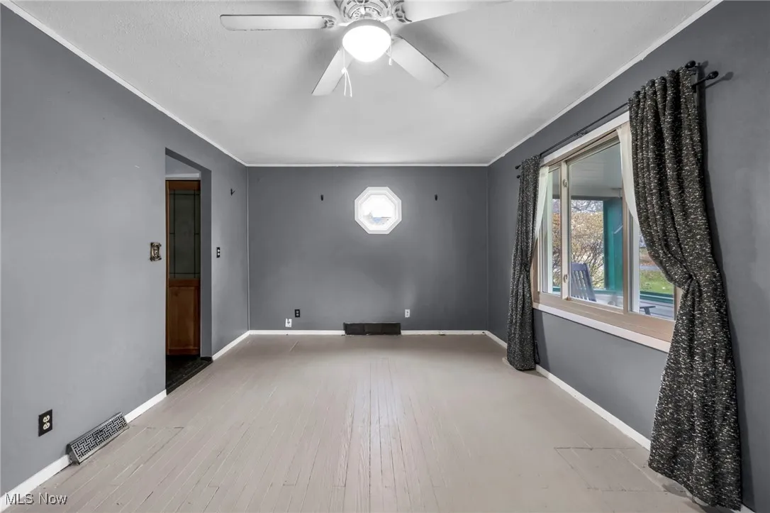 Empty room featuring light wood finished floors, ceiling fan, and ornamental molding