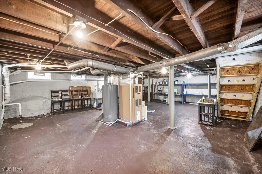 Basement with water heater, heating unit, and drainage system