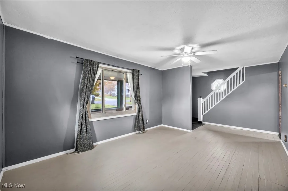 Spare room with stairway, hardwood / wood-style floors, and ceiling fan