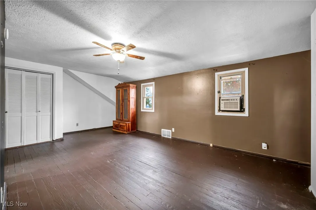 Additional living space with dark wood-style flooring, a textured ceiling, and ceiling fan