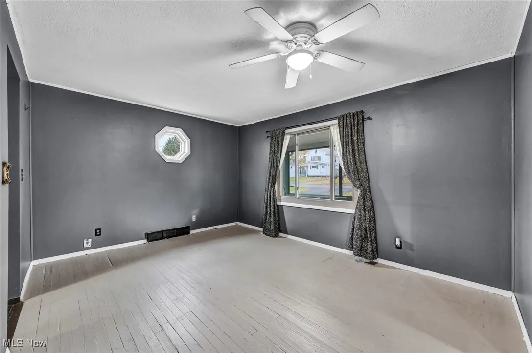 Spare room featuring light wood-type flooring, a ceiling fan, and a textured ceiling