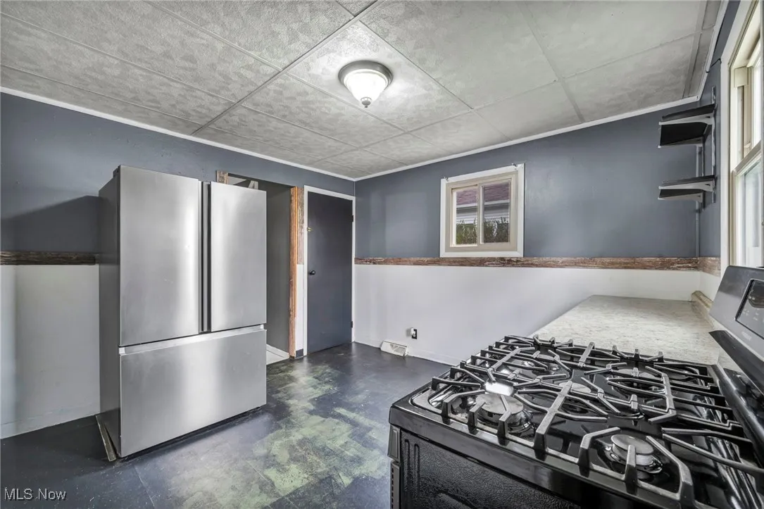 Kitchen with range with gas stovetop, freestanding refrigerator, and dark flooring