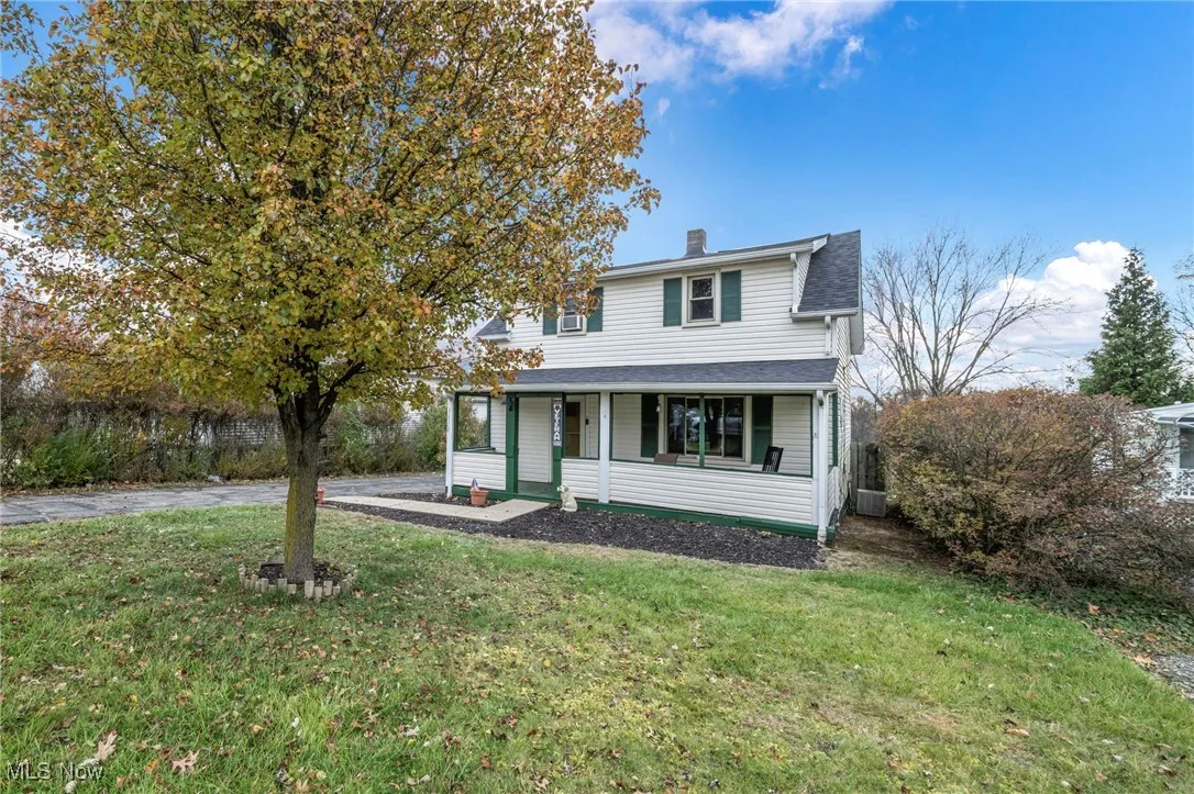 View of front of property with a front lawn, a chimney, covered porch, and roof with shingles