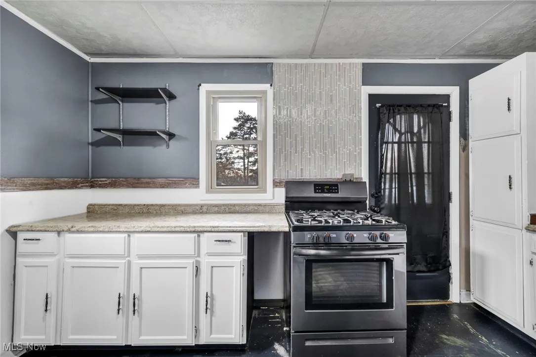 Kitchen featuring white cabinetry, open shelves, and stainless steel range with gas cooktop