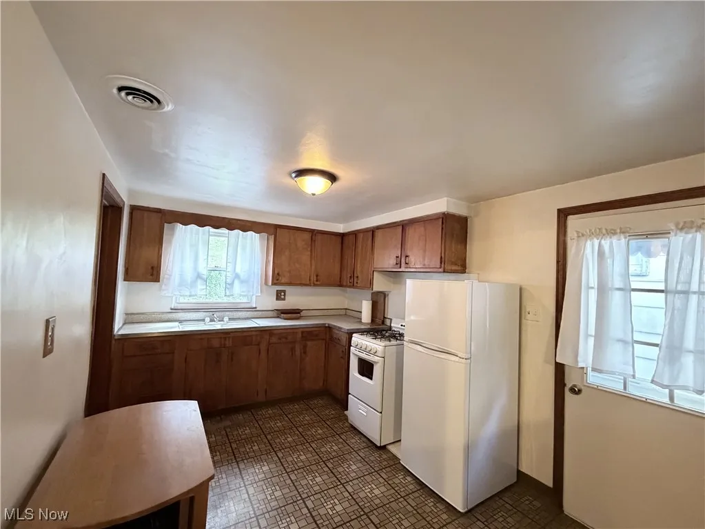 Kitchen featuring white appliances, and brown cabinetry
