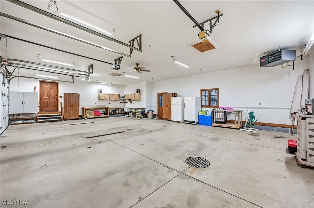 Garage with a heating unit, freestanding refrigerator, and a garage door opener