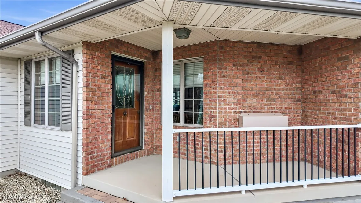 Entrance to property with covered porch and brick siding