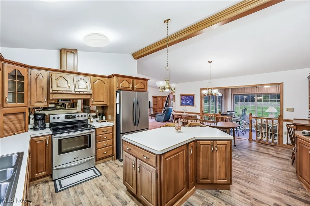 Kitchen featuring stainless steel appliances, brown cabinetry, a chandelier, and light countertops