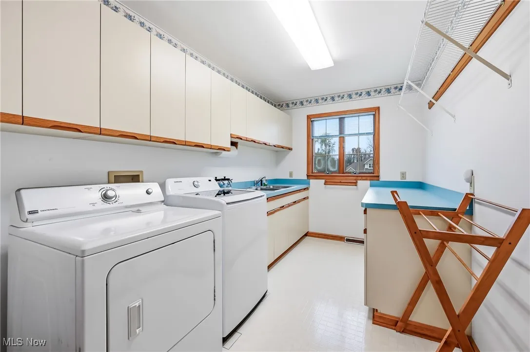 Laundry area featuring light floors, independent washer and dryer, and cabinet space