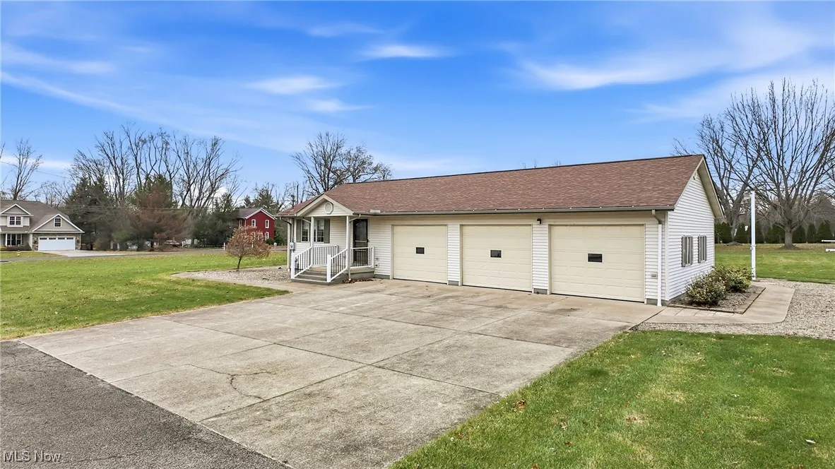 View of front of house featuring a front yard, a shingled roof, and driveway