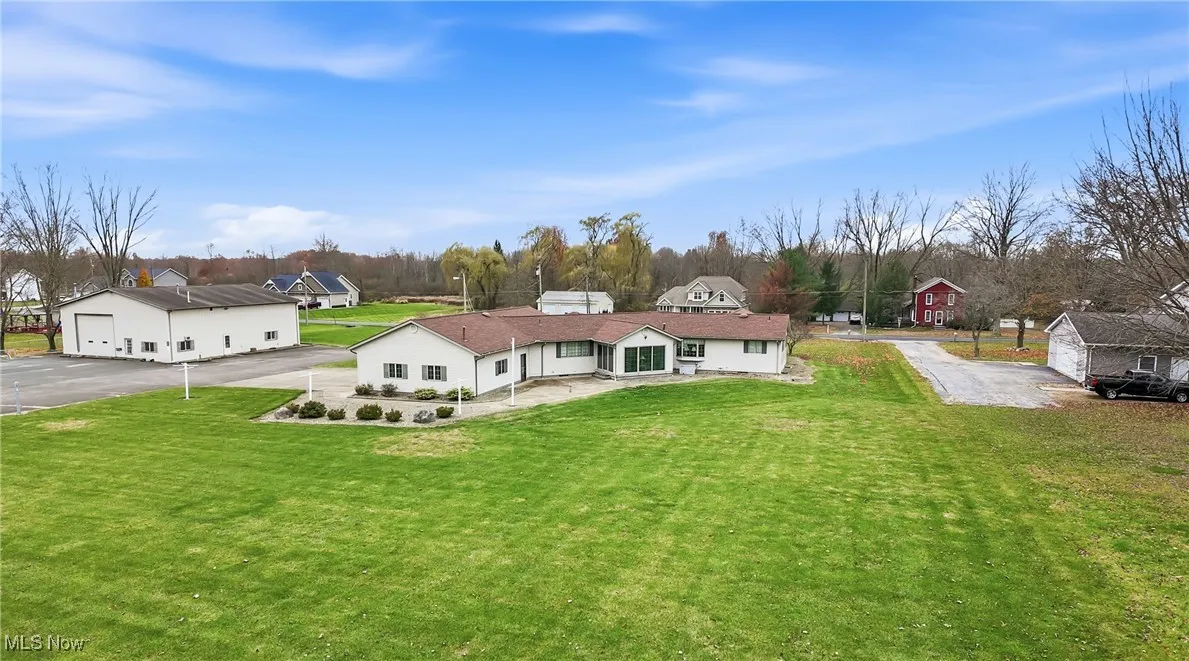 Back of house with a lawn, driveway, a residential view, and a patio