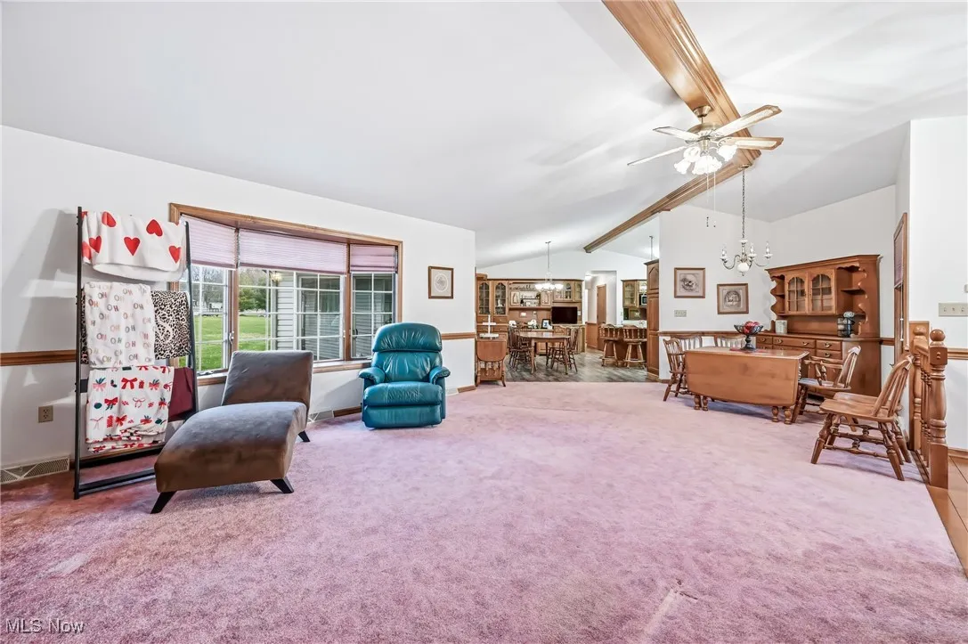 Living area with carpet flooring, ceiling fan, and a chandelier