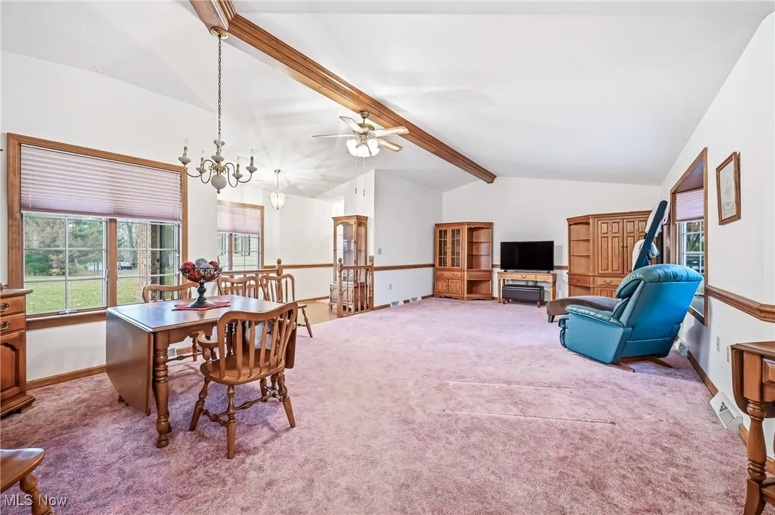 Dining area with light colored carpet, ceiling fan, and a chandelier