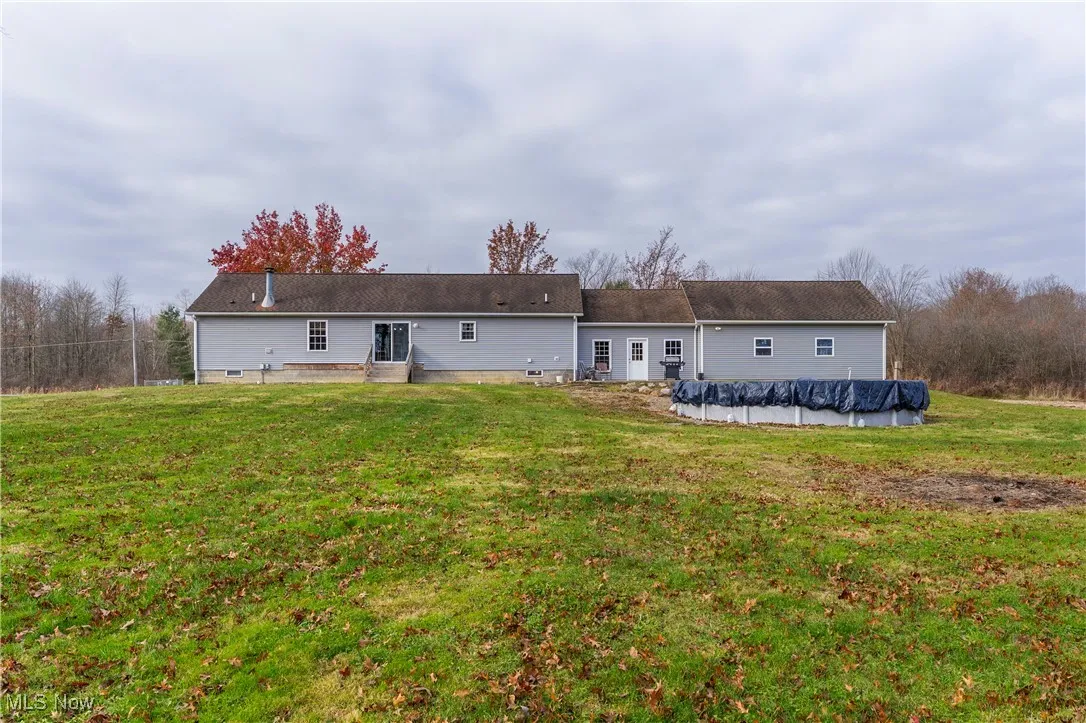 Rear view of property with a lawn, and above ground pool