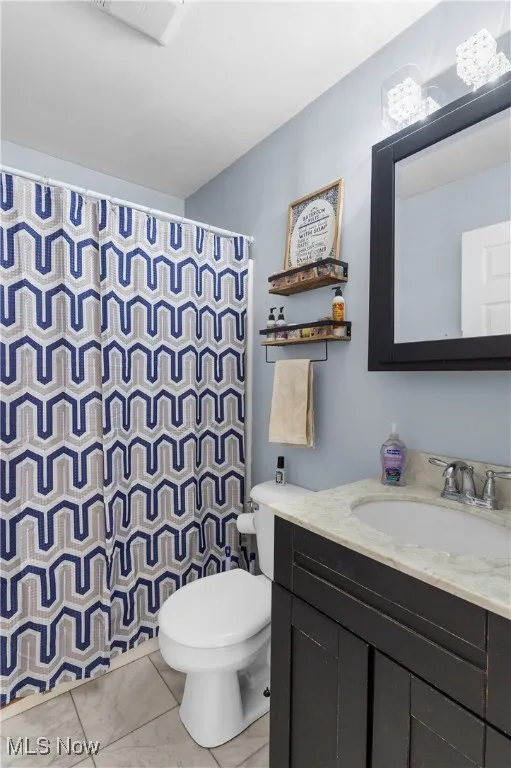 Full bath featuring vanity, a shower with shower curtain, and light tile patterned floors