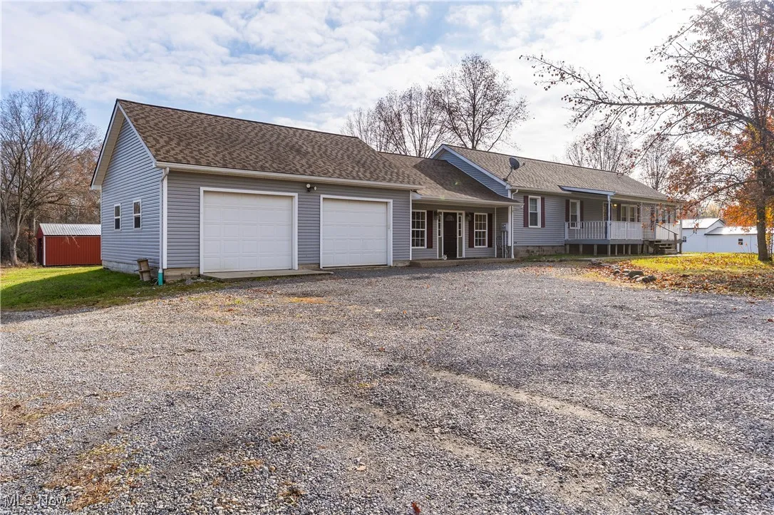Ranch-style house featuring covered porch, gravel driveway, a shingled roof, and a garage