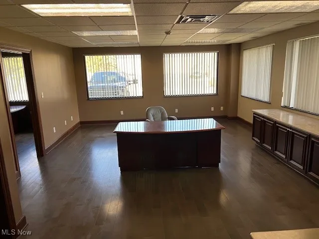 Office area featuring a paneled ceiling, plenty of natural light, and dark wood-style floors