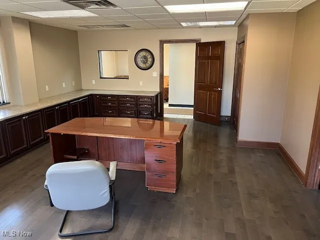 Home office with a drop ceiling and dark wood-style flooring