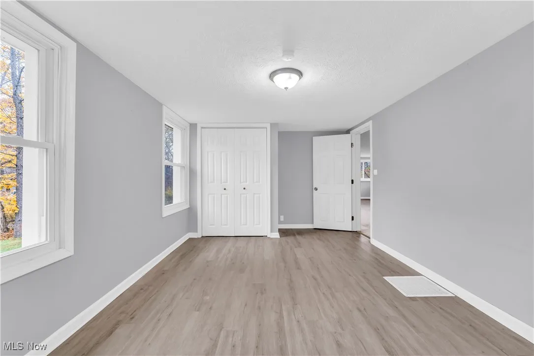 Unfurnished bedroom with a textured ceiling, light wood finished floors, and a closet