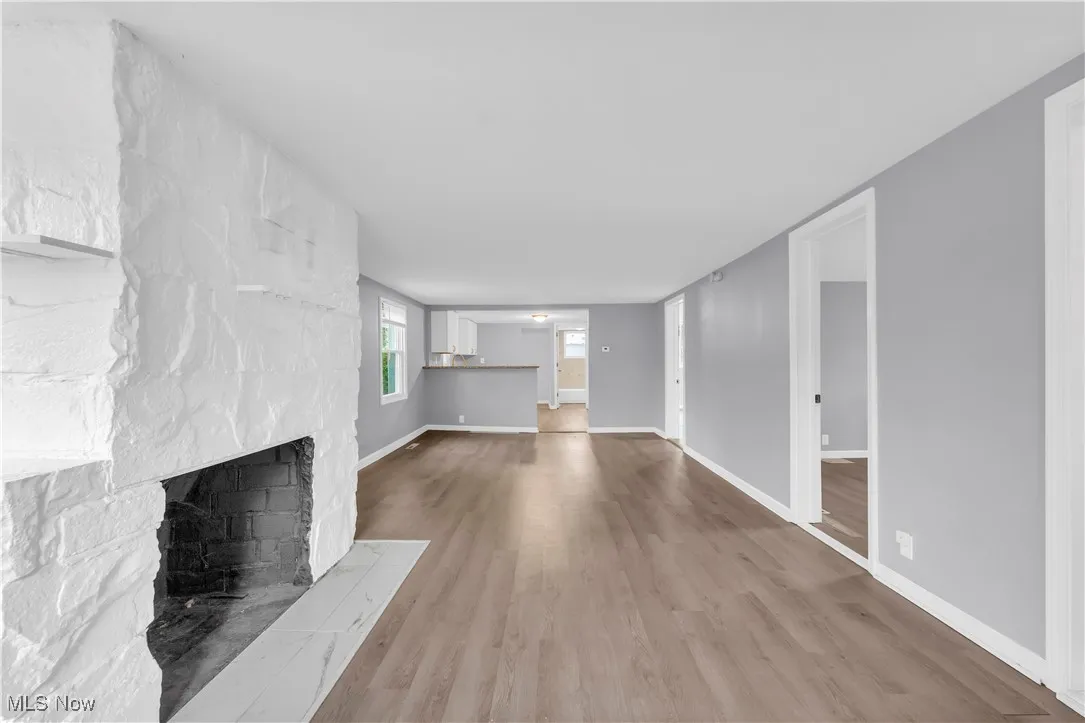 Unfurnished living room with wood finished floors and a large fireplace