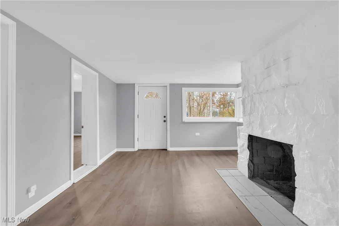 Unfurnished living room with wood finished floors and a large fireplace