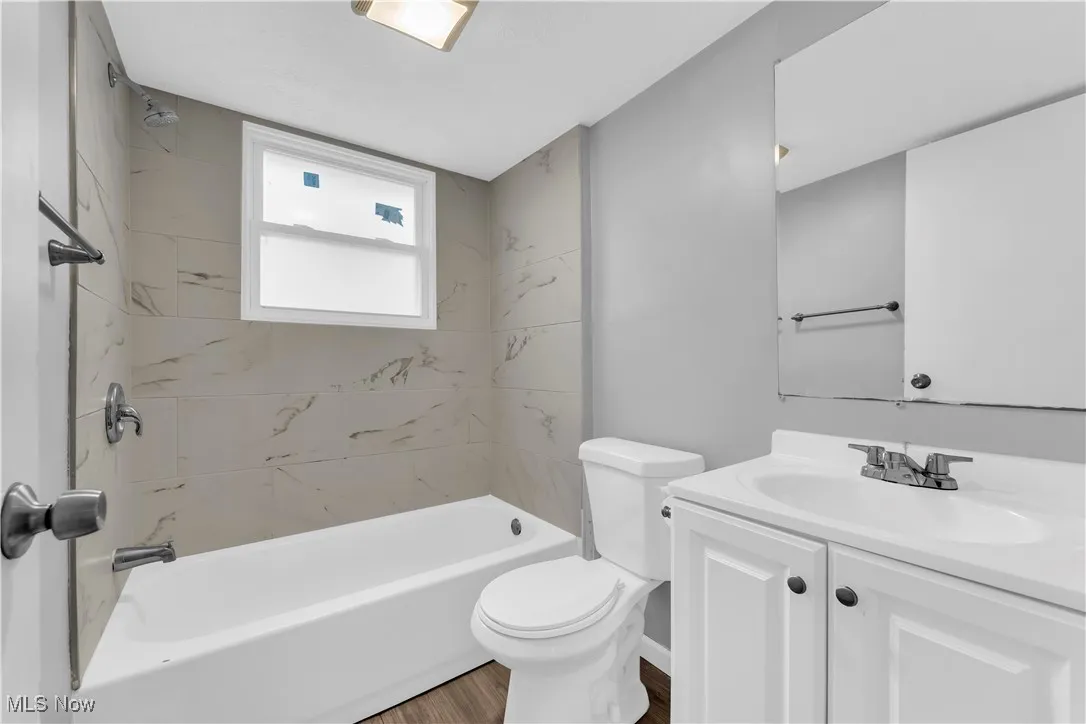 Bathroom featuring vanity, shower / tub combination, and wood finished floors
