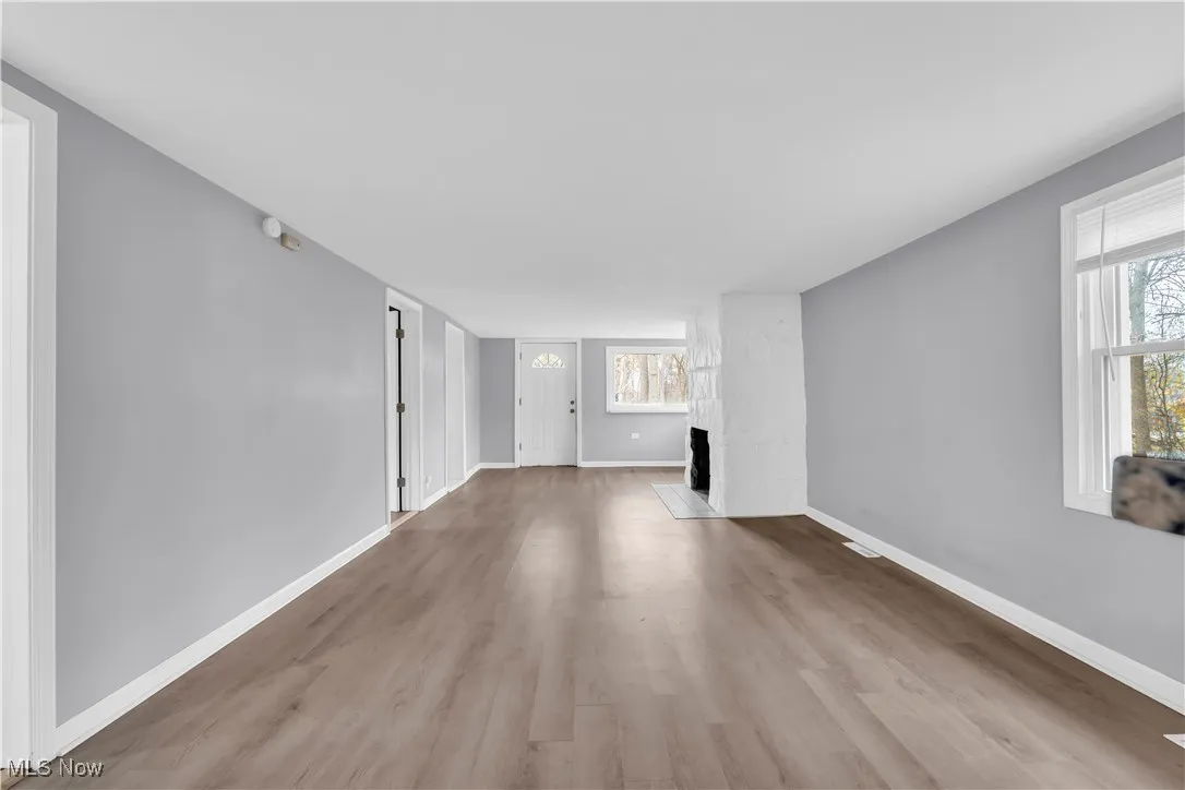 Unfurnished living room featuring wood finished floors and a large fireplace