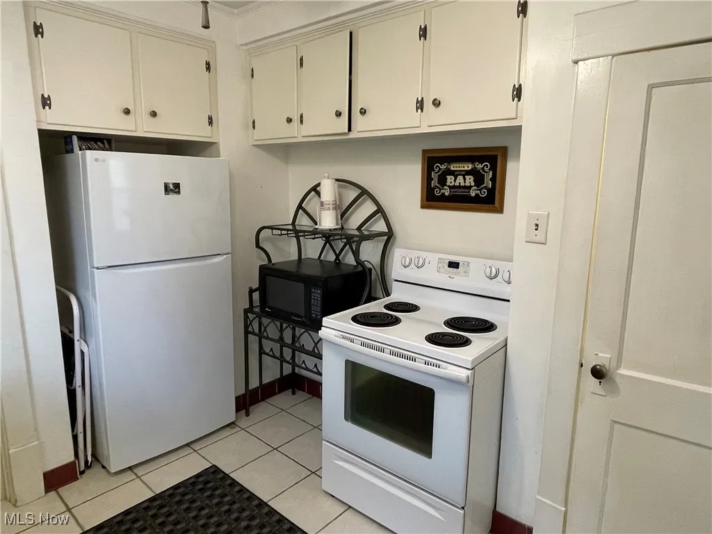 Kitchen featuring white appliances, light tile patterned flooring, and light countertops