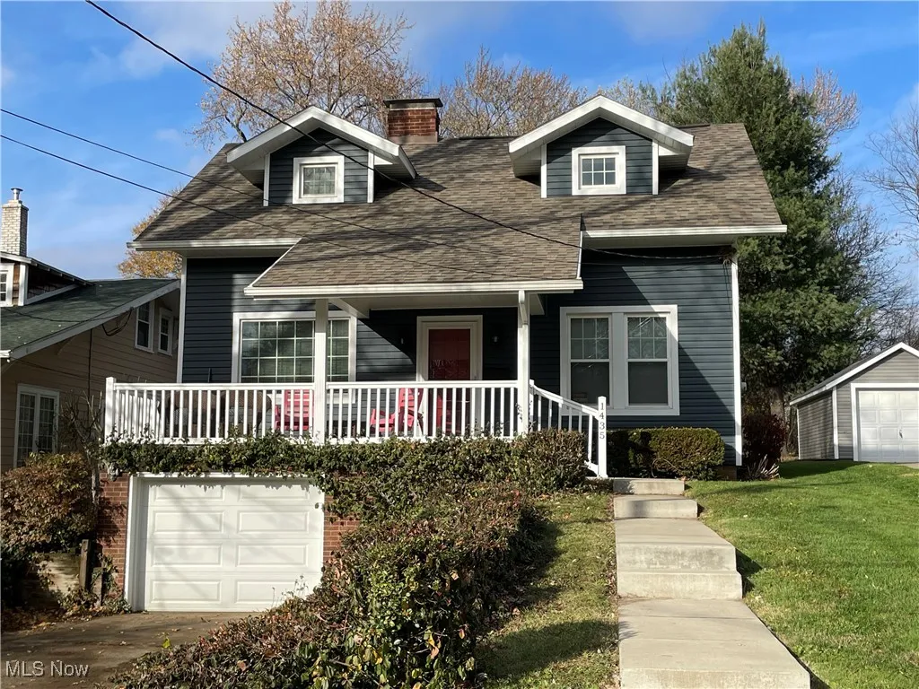 Bungalow-style house featuring a garage, covered porch, a chimney, a shingled roof, and a front yard