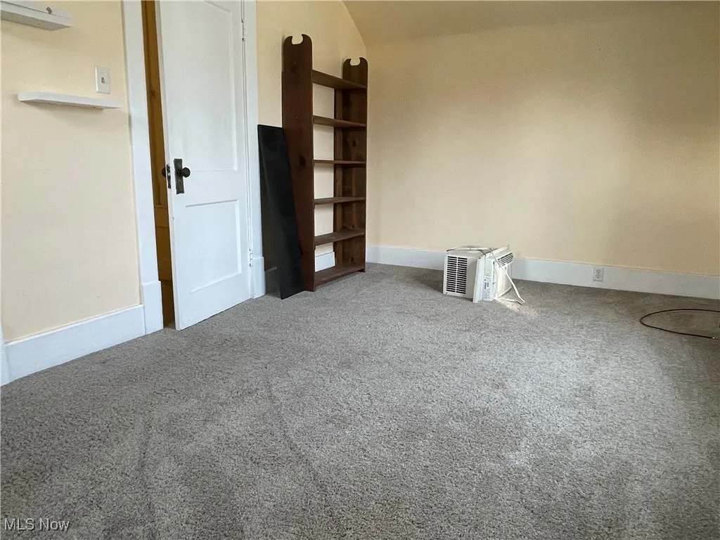 Empty room featuring carpet floors and vaulted ceiling