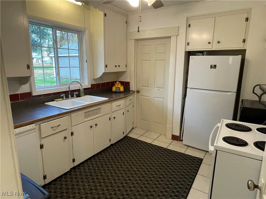Kitchen with white appliances, light tile patterned flooring, white cabinetry, and a ceiling fan
