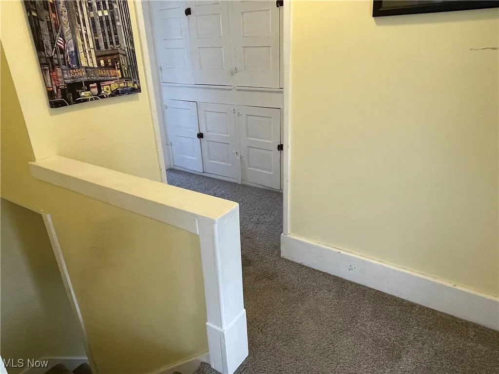 Hallway featuring dark colored carpet and baseboards