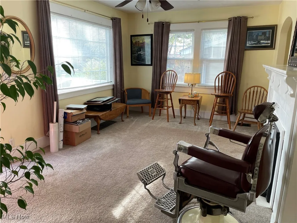 Sitting room with light carpet, healthy amount of natural light, ceiling fan, and a fireplace