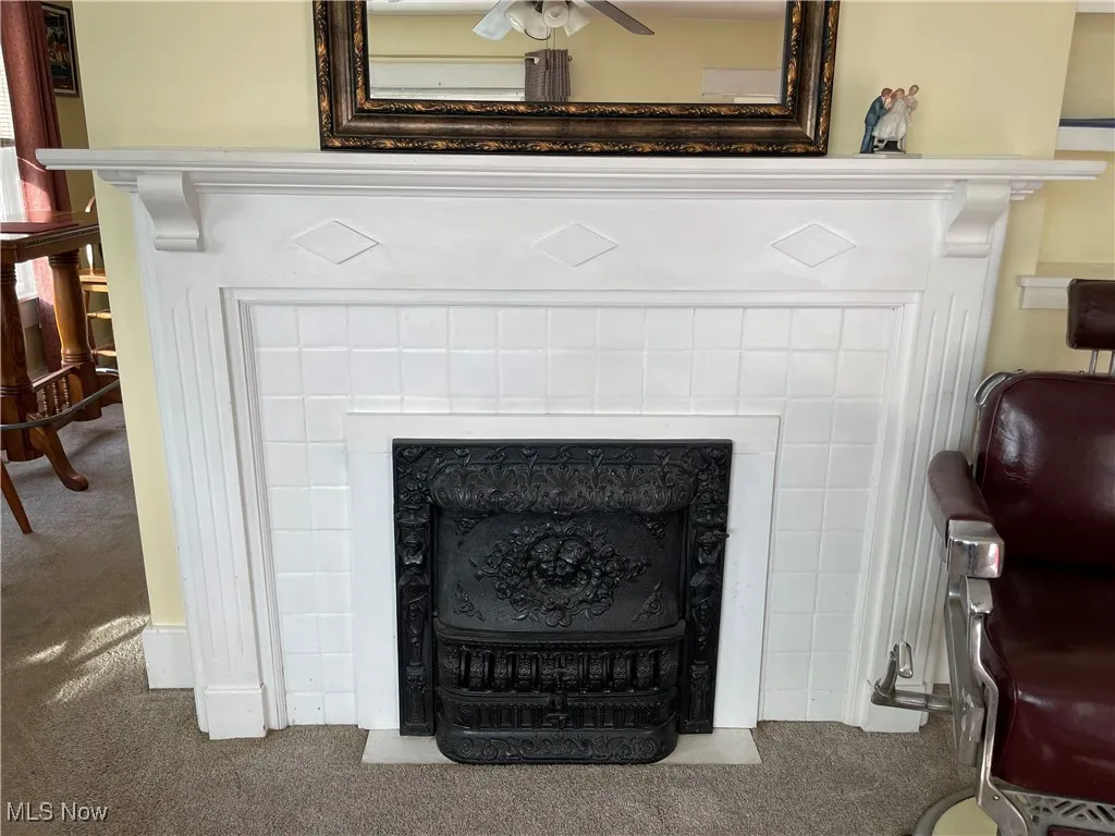 Detailed view of carpet flooring, a tile fireplace, and ceiling fan