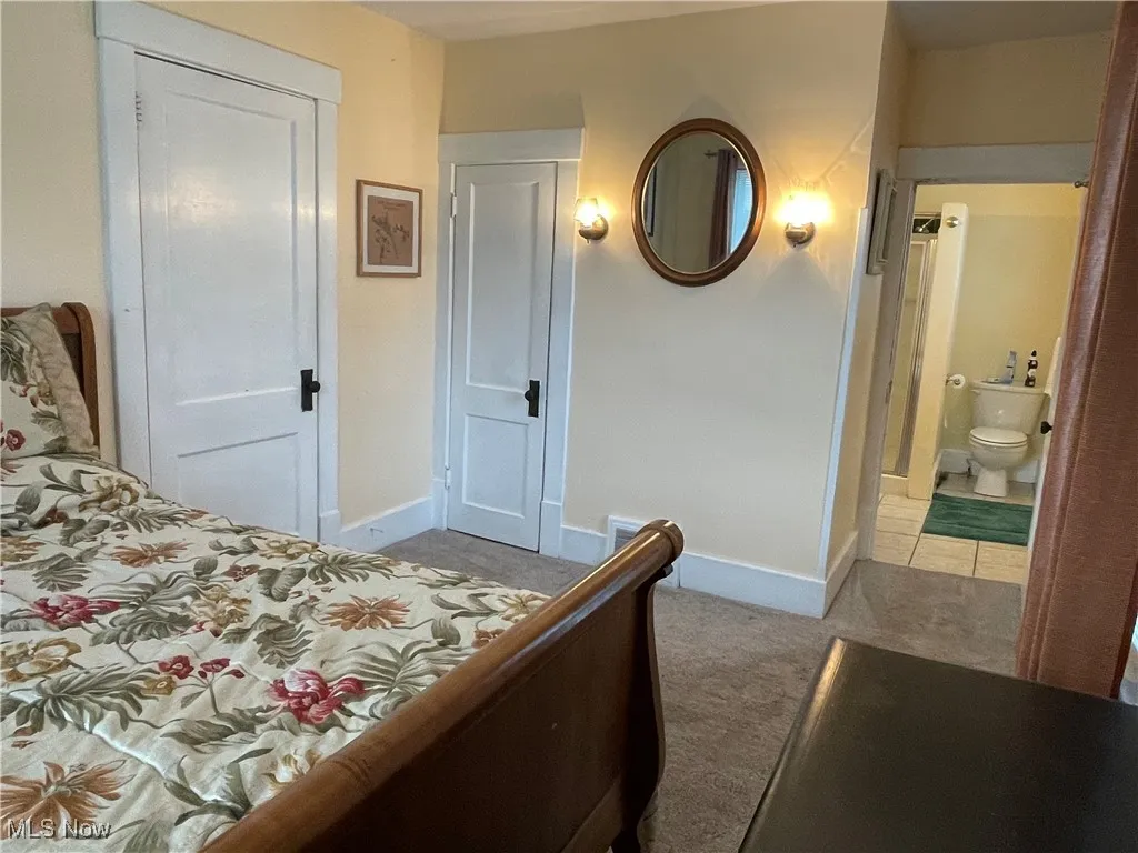 Carpeted bedroom with ensuite bathroom and tile patterned floors