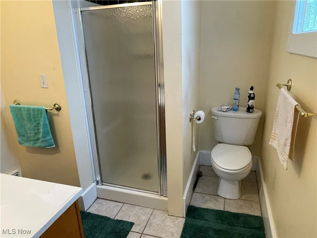 Full bath with light tile patterned floors, a stall shower, and vanity