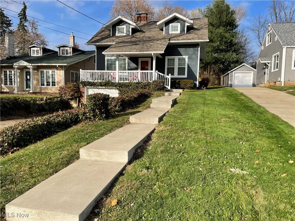 Cape cod house with a porch, an outbuilding, a chimney, a front lawn, and roof with shingles