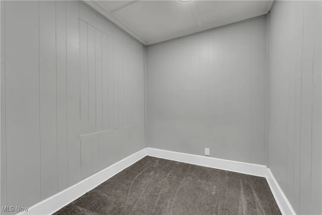 Empty room featuring dark carpet and wooden walls