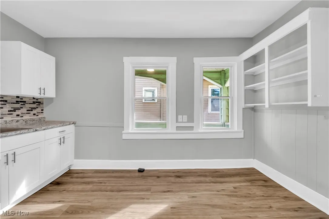 Unfurnished dining area featuring light wood-type flooring and wainscoting