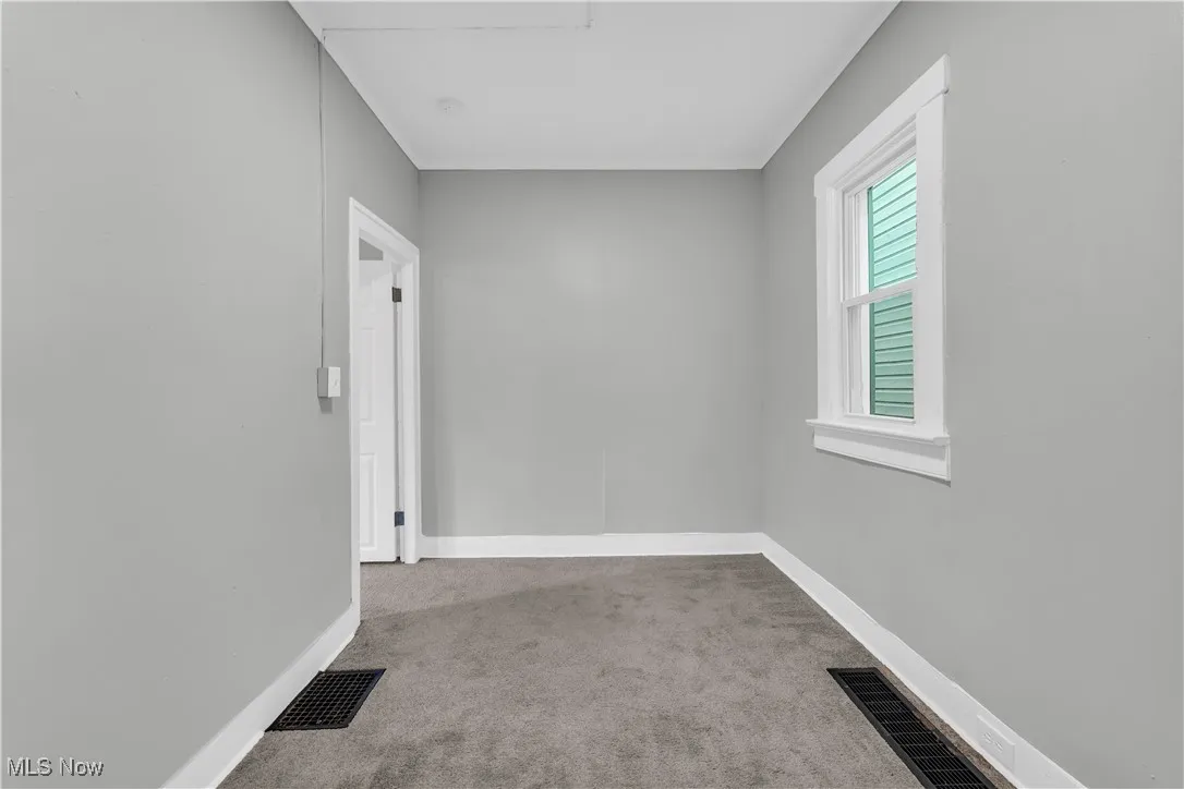 Unfurnished room featuring light carpet and baseboards