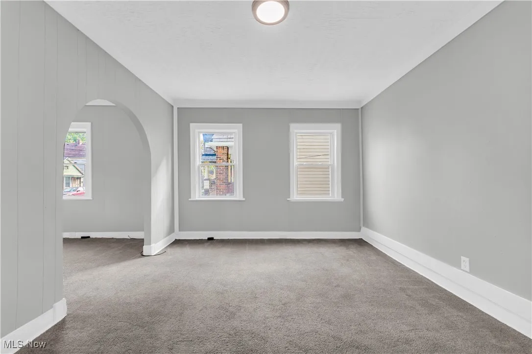 Carpeted spare room with arched walkways and ornamental molding