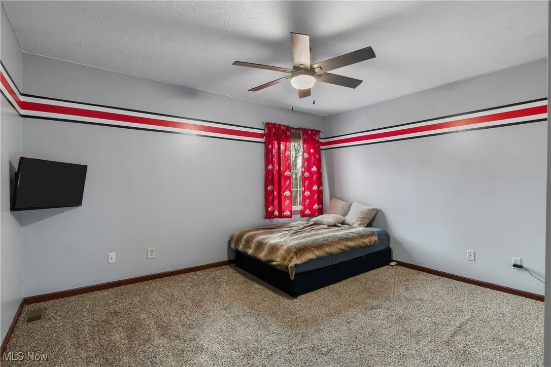 Bedroom featuring carpet flooring, a textured ceiling, and ceiling fan