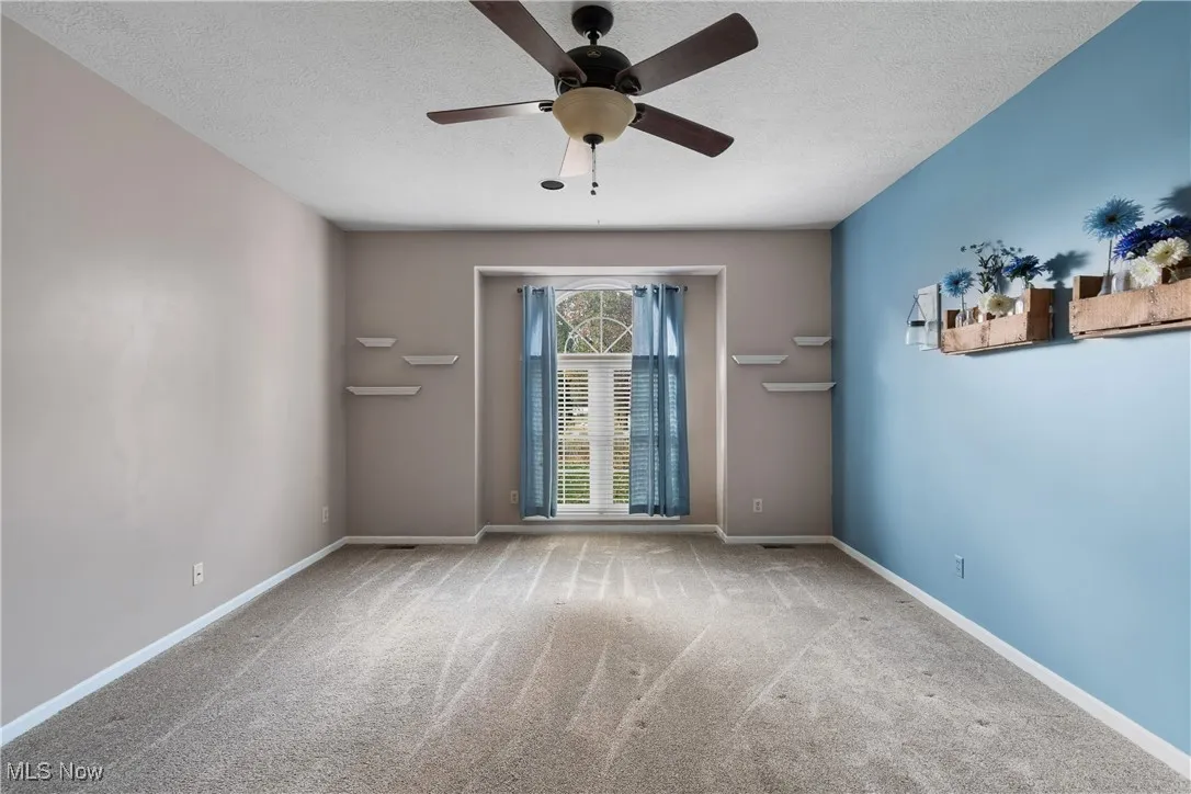 Unfurnished room with carpet, a ceiling fan, and a textured ceiling