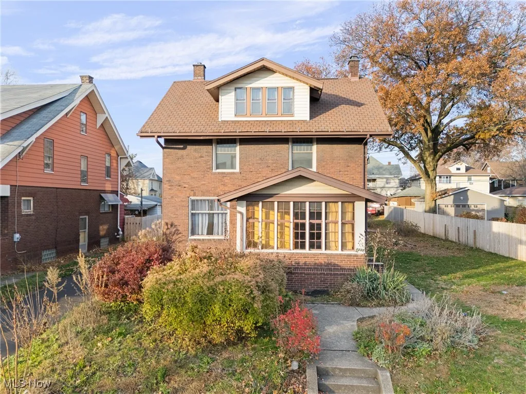 Back of property with brick siding, a sunroom, roof with shingles, and a chimney