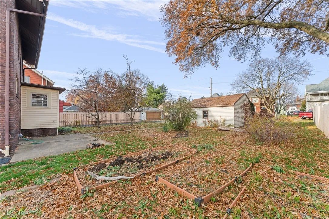 Fenced backyard featuring a vegetable garden, a patio, and a shed